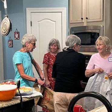 Four women engaged in conversation in a kitchen setting.