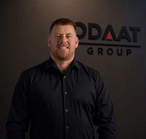 Man smiling in front of a company logo.