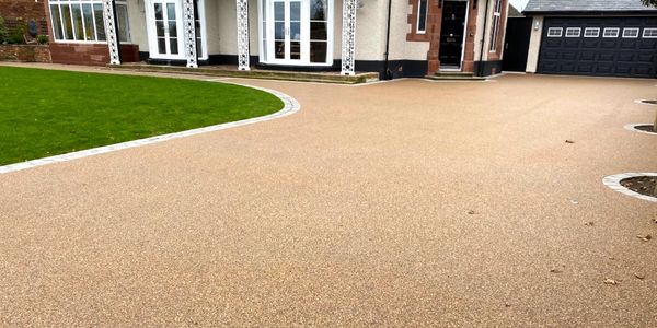 Smooth resin driveway with curved borders and green lawn at a residential house.