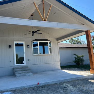 Newly constructed covered patio with ceiling fan and door.