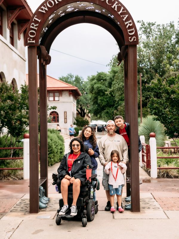 Family posing under Fort Worth Stockyards archway outdoors.