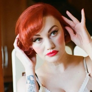Woman with red hair styling her hair.