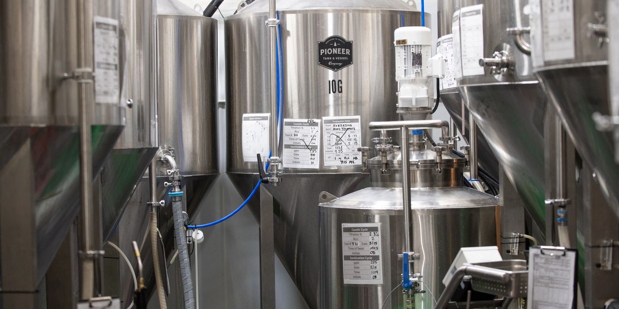 Interior of a brewery with stainless steel fermentation tanks and equipment.