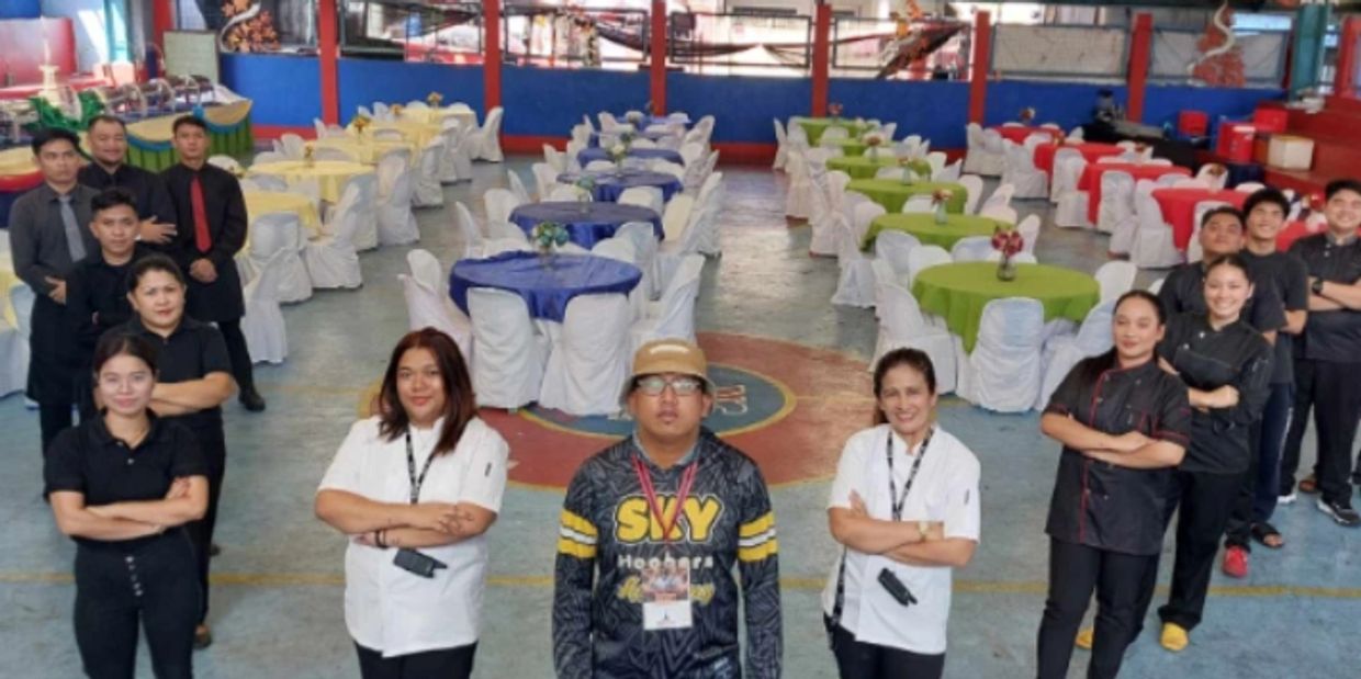 Group of staff standing confidently in a colorful event hall with decorated tables.
