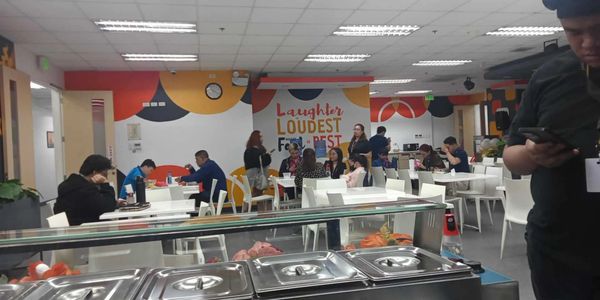 People dining and socializing in a colorful cafeteria with motivational wall art.
