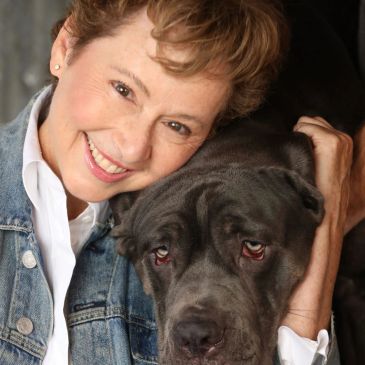 Woman smiling and hugging a large black dog.