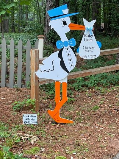 Stork holding a yard sign to announce a new baby.