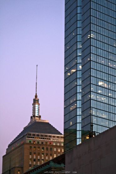Two skyscrapers at dusk with one reflecting twilight sky.