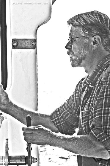 Black and white photo of a focused man steering a boat.