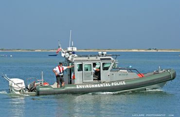 Environmental Police boat patrolling calm waters with an officer on board.