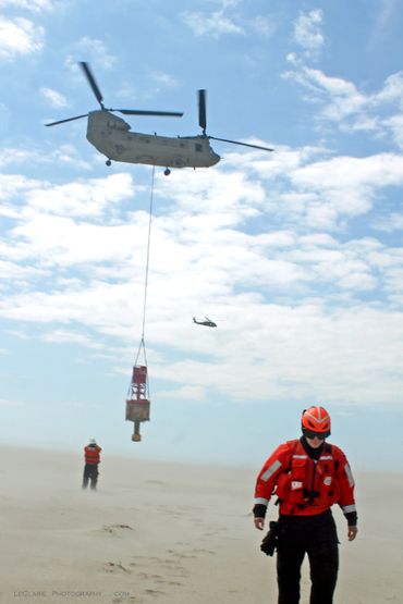 Rescue personnel and helicopters conducting an aerial operation on a sandy beach.