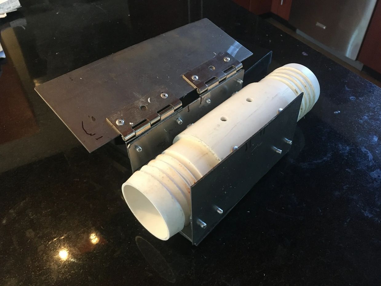 A white cylindrical pipe secured with metal brackets and hinges on a black surface.
