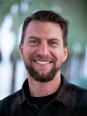 A man smiling under a beach piling.