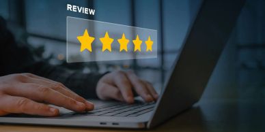 Person typing on laptop with a five-star review graphic.