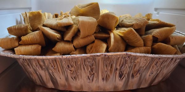 Aluminum tray filled with wrapped tamales.