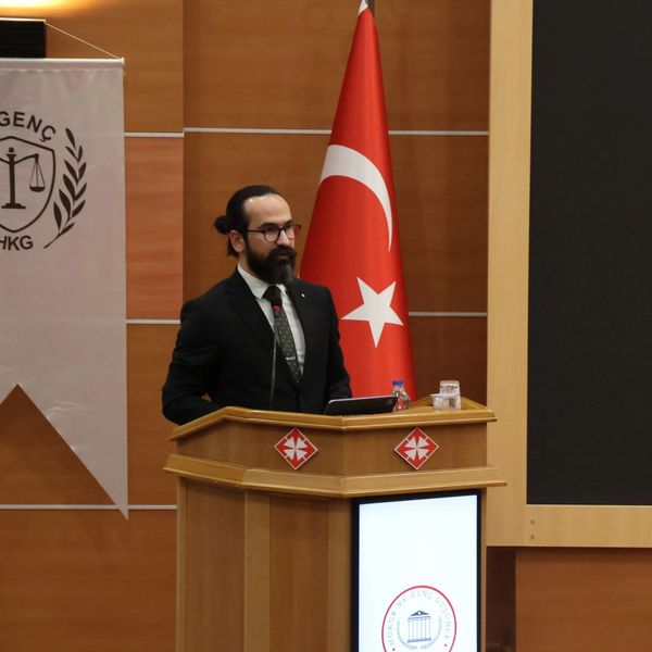 Türk bayrağı önünde kürsüde konuşan adam.