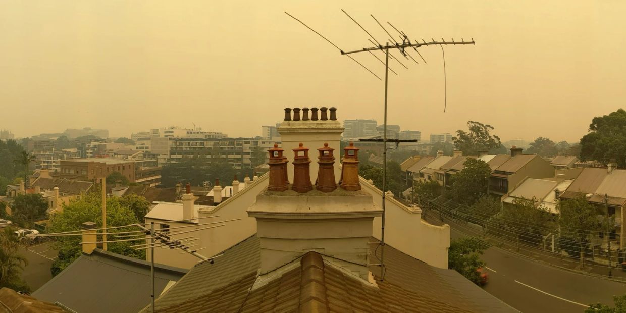 Hazy cityscape with yellow sky and rooftops.