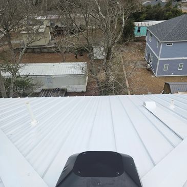 View from a white metal rooftop overlooking houses and trees below.