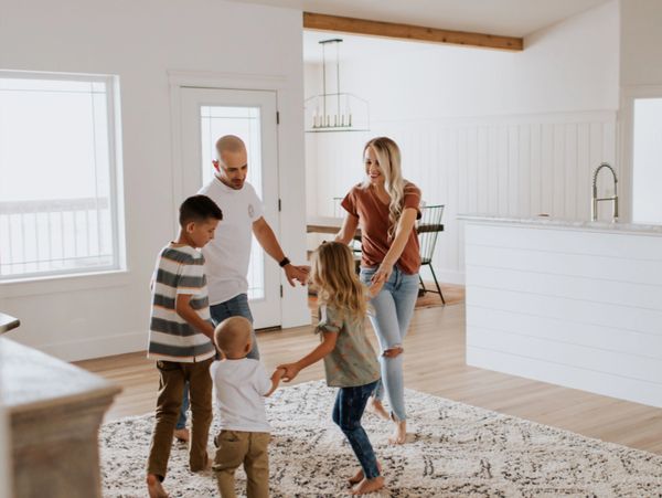 A family joyfully playing and holding hands in a bright living room.