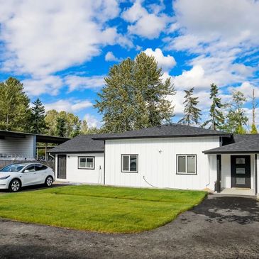 Modern white house with a trimmed lawn and a white car parked outside.