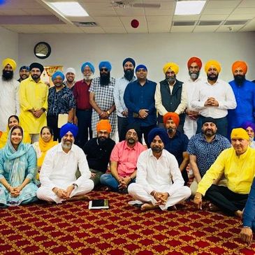 Group of Sikh men and women posing indoors.