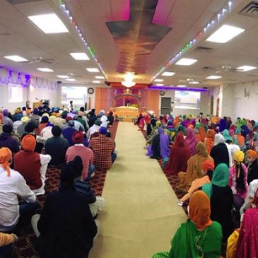 Congregation gathered inside a Sikh prayer hall.