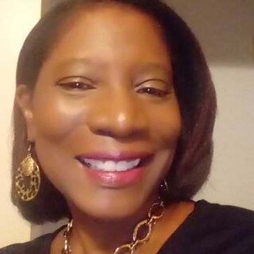 Smiling woman with short hair wearing gold earrings and necklace.