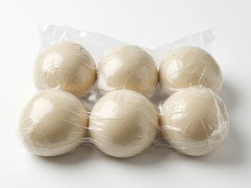 Six dough balls wrapped in clear plastic.