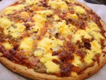Breakfast pizza with scrambled eggs and sausage.