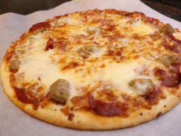 Cheese and sausage pizza on parchment paper.