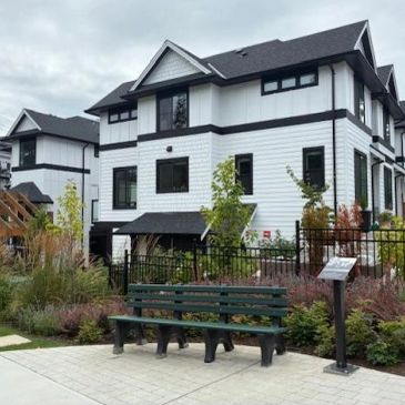 Modern white and black house with a park bench outside.