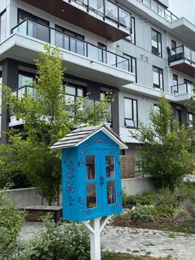 A small blue book exchange cabinet in front of an apartment building.