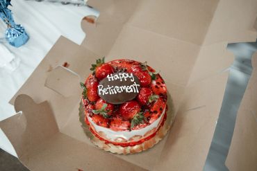 A retirement cake with strawberries and cherries.