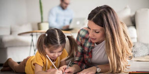 Mother and daughter drawing together on the floor.