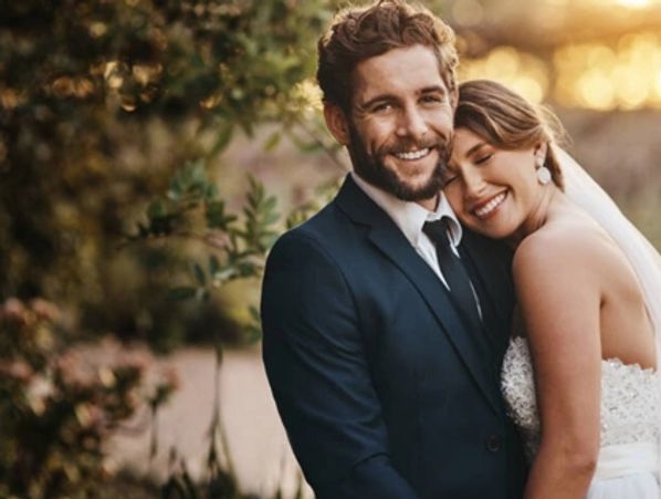 A newly-wed couple smiling posing for a picture.