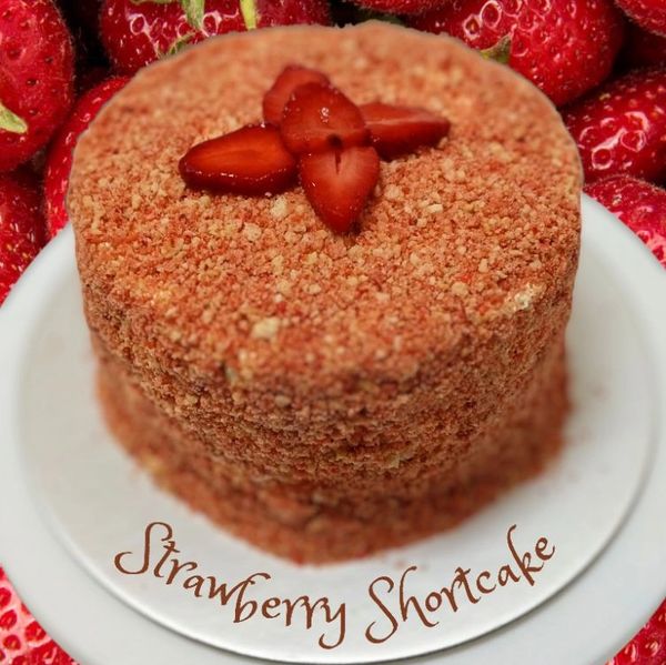 Strawberry shortcake topped with fresh sliced strawberries on a white plate.