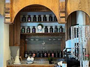 Beautiful wooden tea bar with herbal jars, glassware, and elegant decor.