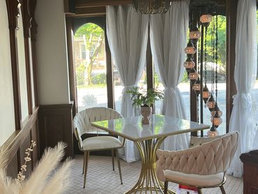 Elegant seating area with gold-accented table, plush chairs, and natural light.