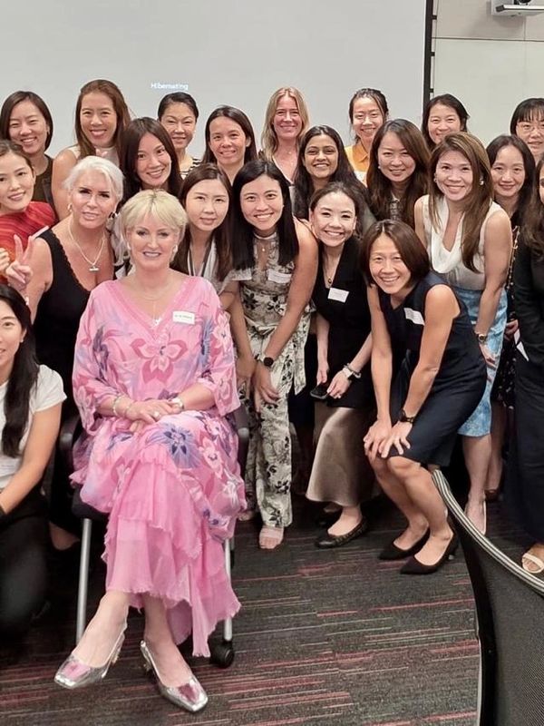 A group of women posing for a cheerful group photo indoors.