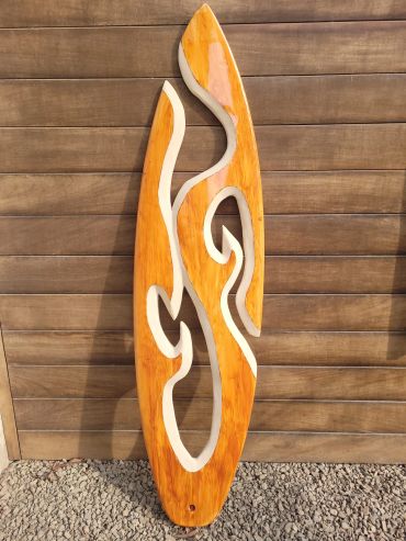 Wooden abstract sculpture with cut-out design against a wooden wall.