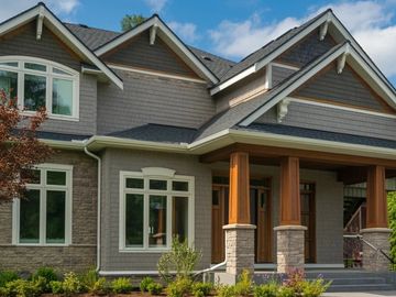 Modern house exterior with wooden pillars and large windows.