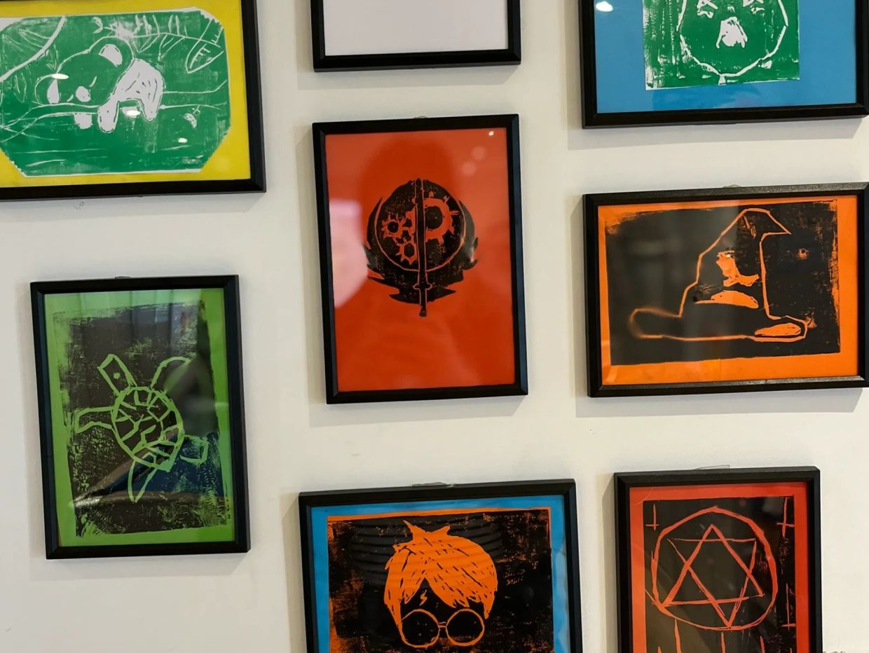 Framed artworks of animals and symbols on a wall.