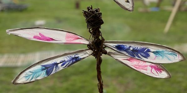Decorative dragonfly with feathered wings outdoors.