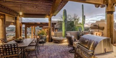 Cozy outdoor patio with rustic wooden beams, dining area, and barbecue grill.