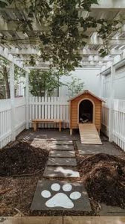 Cozy backyard doghouse with a ramp and paw print stepping stones.