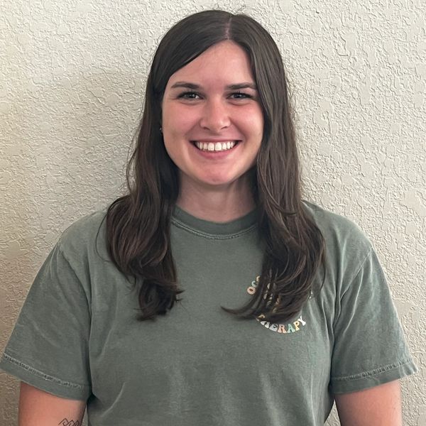 Smiling woman with long dark hair in a green t-shirt.