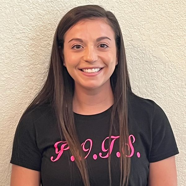 Smiling woman wearing a black shirt with pink letters.
