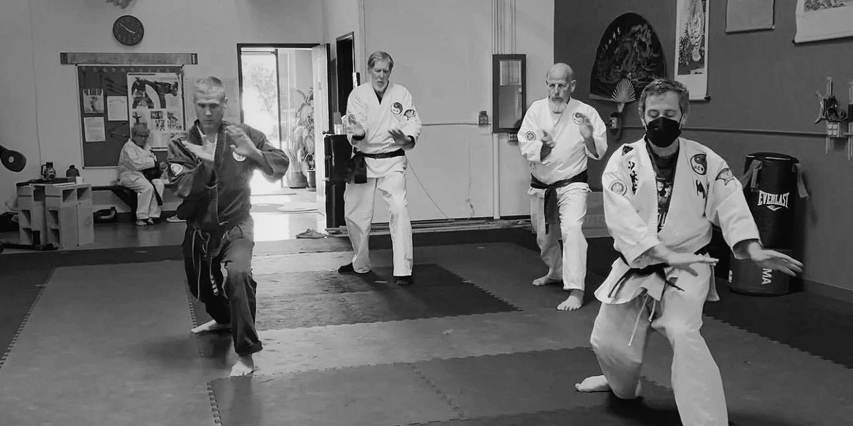 Four martial artists practicing tai chi in a dojo.