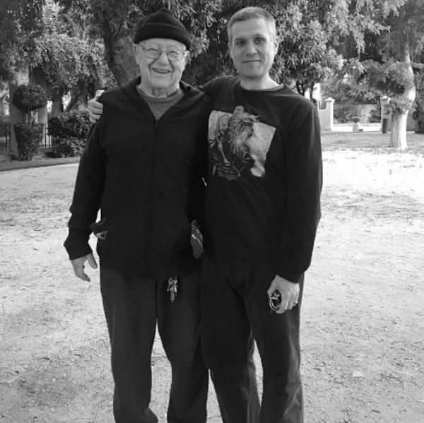 Two men posing outdoors with arms around each other.