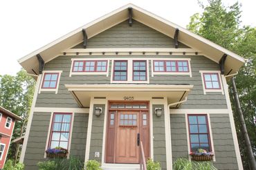 4 color Craftsman cottage with big overhangs and large gable brackets and wood front door